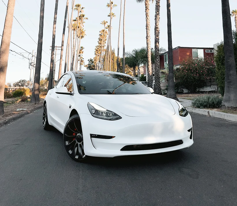 Na środku zdjęcia znajduje się magazyn z dużym logo W8 на dachu oraz mniejszymи logo над kilькома wejściami. Wokół magazину є parking з багатьма автомобілями.